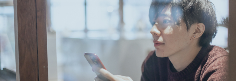 スマートフォンを見つめる男性の画像