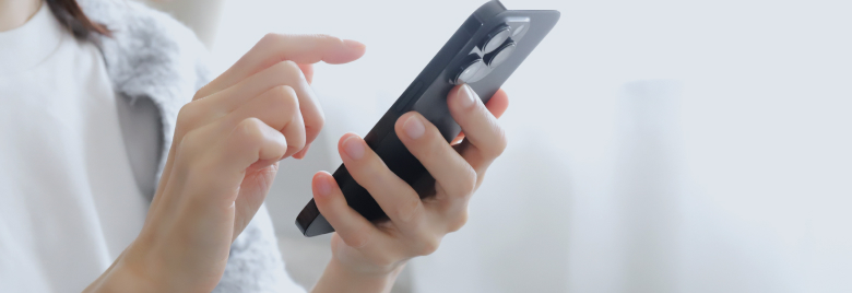 左手でスマートフォンを持って右手で操作しようとしている様子