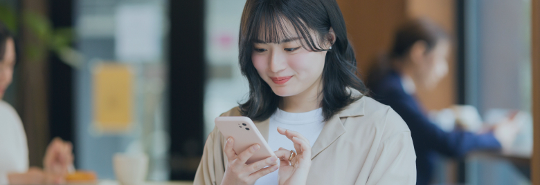 右手に持ったスマートフォンを見つめながら微笑んでいる女性