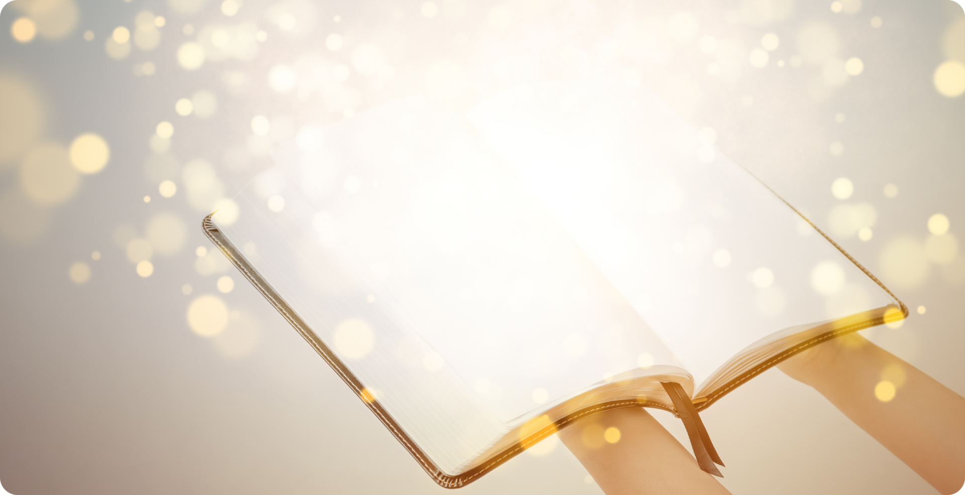 両手の上に乗せた開いた本からキラキラとした小さな光りの玉が飛び出している様子